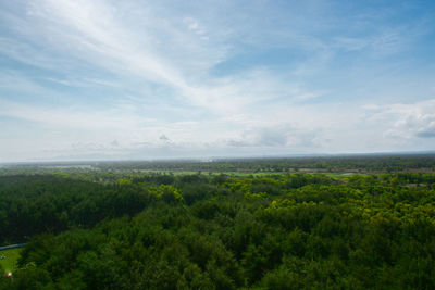 Scenic view of green landscape and sea against sky