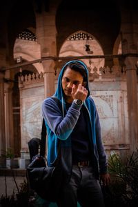 Young woman using phone while standing in corridor