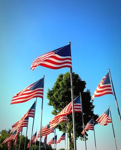 Low angle view of american flag against clear blue sky