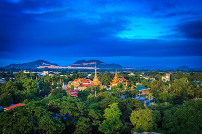 High angle view of trees and buildings against blue sky