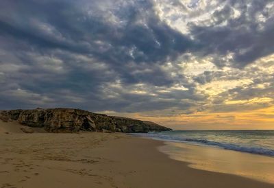 Scenic view of beach against cloudy sky
