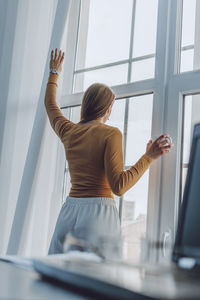 Rear view of woman standing by window