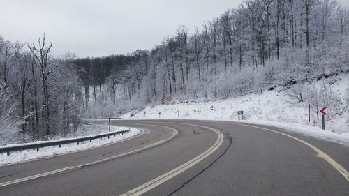 Road amidst snow covered trees against sky