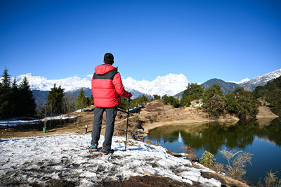 Rear view of man standing on snow against sky