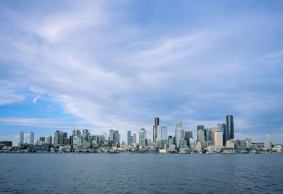 Sea by modern buildings against sky in city