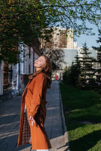 Young woman standing against trees