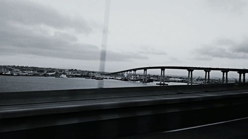 Bridge over river against cloudy sky