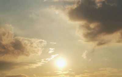 Low angle view of sunlight streaming through clouds