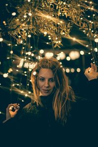 Portrait of woman with illuminated christmas lights at night