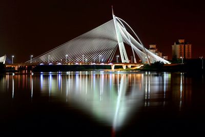 Illuminated bridge over river at night