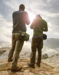 Photographer on cliff with camera viewfinder in his face. nature photographer takes photos with dslr