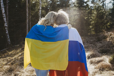 Rear view of women wrapped in ukrainian and russian flags