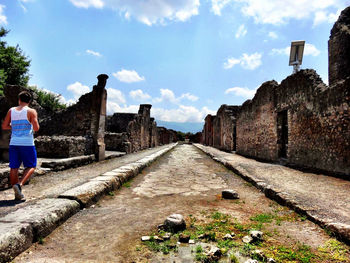 Walkway amidst wall against cloudy sky on sunny day