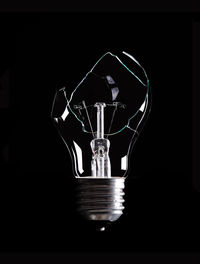 Close-up of illuminated light bulb against black background