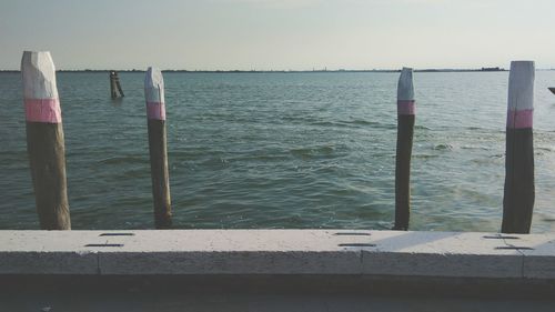 Wooden posts on sea against sky