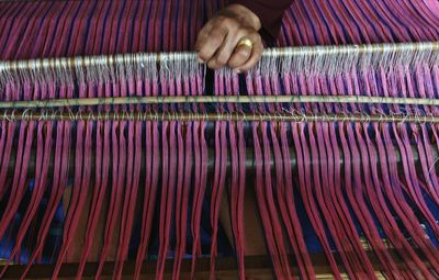 Cropped image of worker working on loom in textile factory
