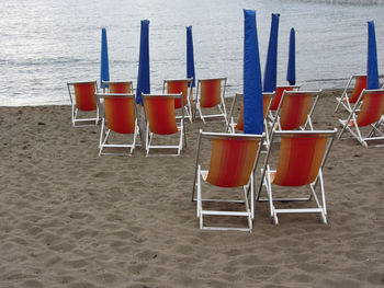 Empty chairs on beach against sea