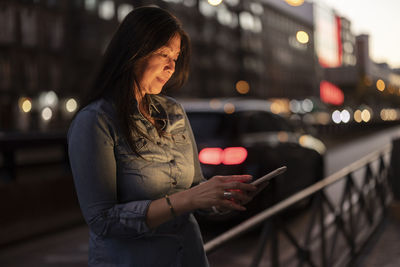 Mature woman using smart phone at dusk