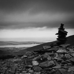 Stack of stones on rock against sky