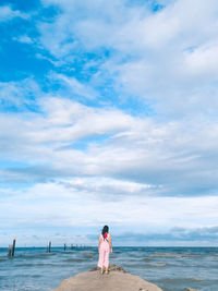 Rear view of friends standing on beach against sky