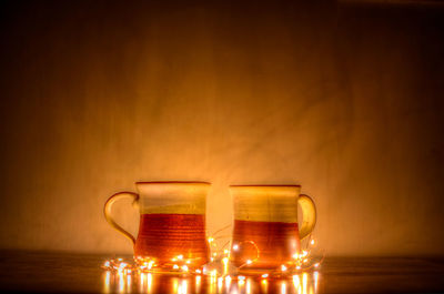 Digital composite image of illuminated candles on table against wall