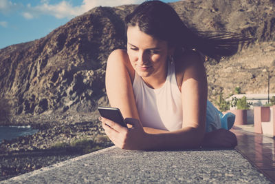 Woman with hand in hair lying on retaining wall