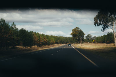 Road amidst trees against sky