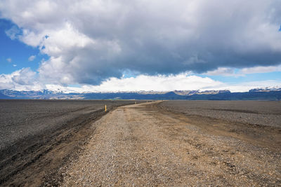 Empty pathway on lava sand in highland amidst volcanic landscape against sky