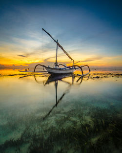 Nautical vessel in sea against sky during sunset