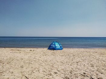 Deck chairs on beach against clear sky