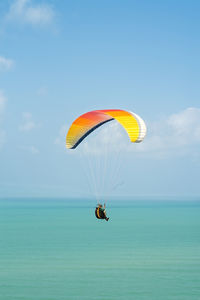 Low angle view of person paragliding against sky