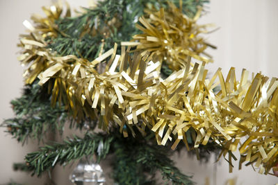 Wrapping golden tinsel around an artificial christmas tree