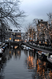 Sailboats moored in river by buildings against sky in city