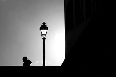 Low angle view of silhouette street light against building