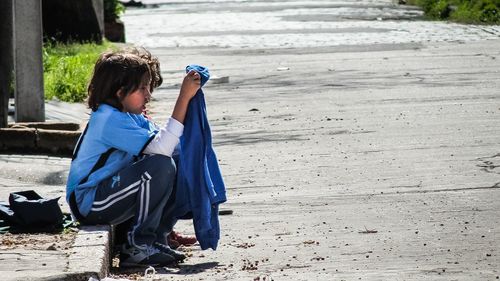 Side view of boy sitting on land