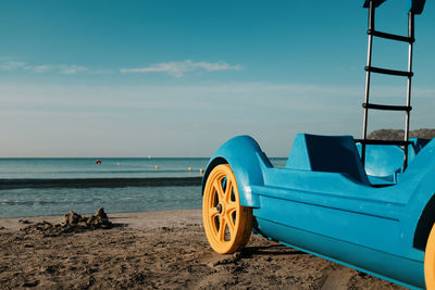 Ladder on car at beach against blue sky