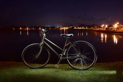 Bicycles by lake against sky at night