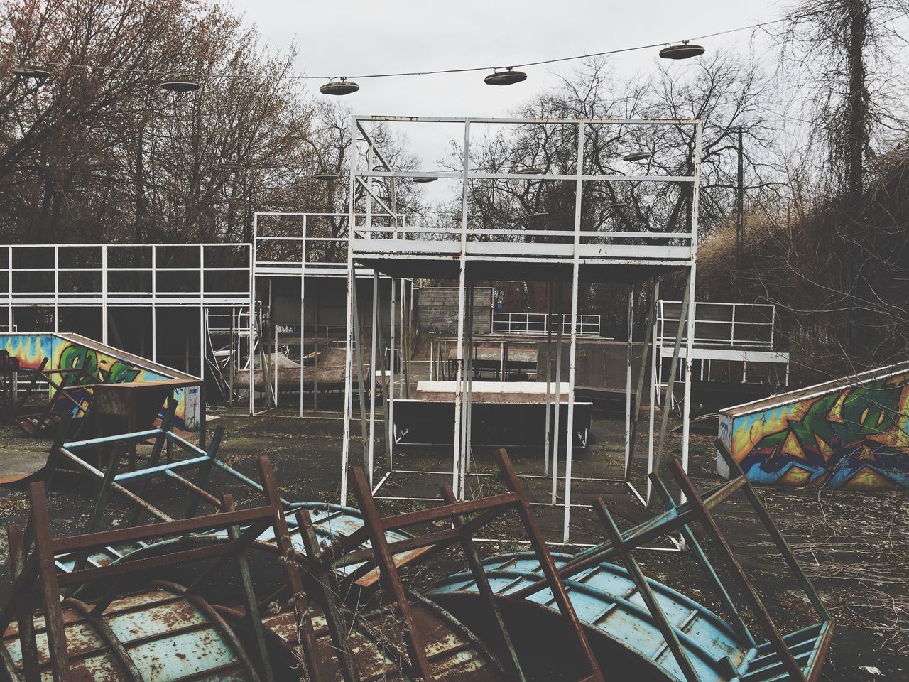 tree, built structure, architecture, metal, clear sky, sky, lighting equipment, building exterior, low angle view, street light, railing, outdoors, metallic, no people, day, city, amusement park, growth, incidental people, chainlink fence