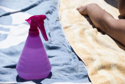 Cropped hand of person with spray bottle on blanket during sunny day