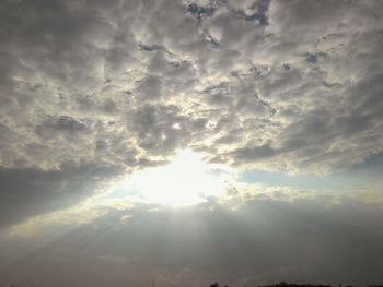 Low angle view of sun shining through clouds