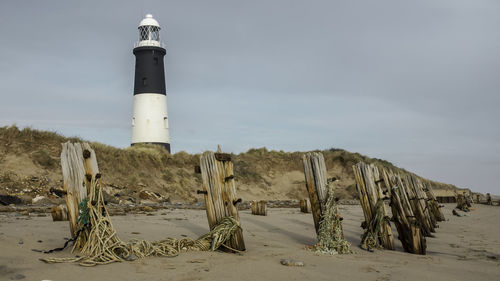 Lighthouse on beach against sky