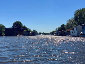 River flowing amidst buildings against clear blue sky