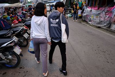 Rear view of people walking on street in city