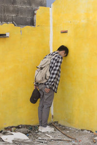 Man standing against yellow wall