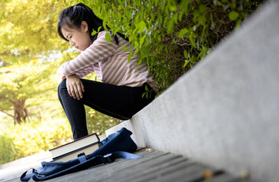 Side view of woman sitting on plants