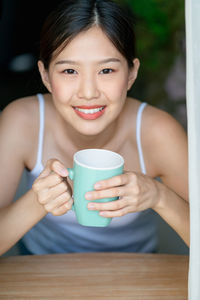 Portrait of smiling woman holding coffee cup