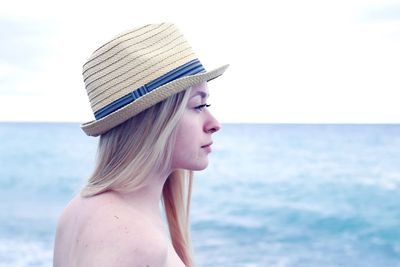 Close-up of young woman in hat against sea