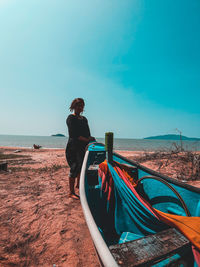 Woman standing at beach against blue sky