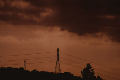 Low angle view of silhouette electricity pylon against sky during sunset