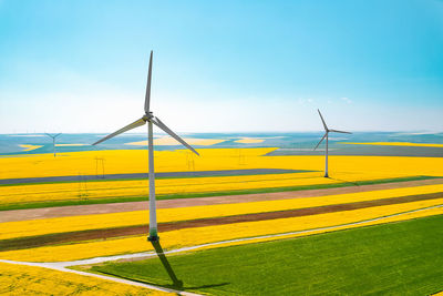 Aerial view of wind turbines farm on agricultural field in summer